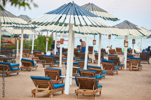 Umbrellas and sun loungers at luxury tropical resort on coral beach in the Red Sea. Resort complex on Red Sea. Typical resort beach.