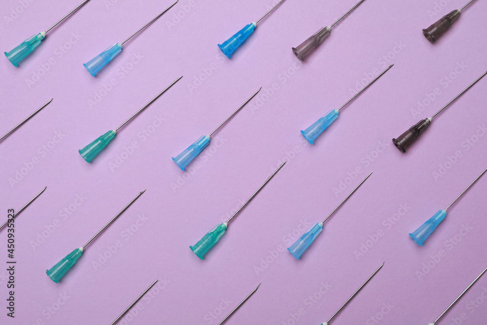 Disposable syringe needles on violet background, flat lay Disposable syringe needles on violet background, flat lay