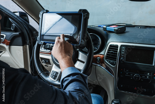 Car diagnostic. Technical inspection, car electronics. A Latin man holds a digitizing device.