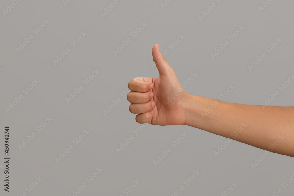 Teenage boy showing thumb up on light background, closeup