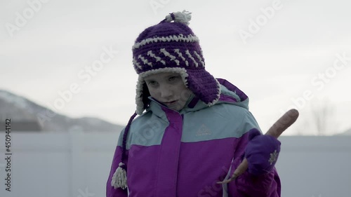 Bored girl waits with a carrot to build a snowman but there is no snow.