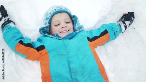 Boy makes snow angels in the snow