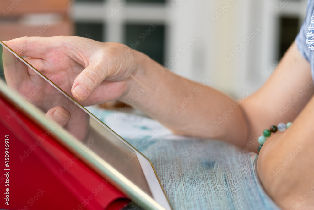 senior asian woman using digital tablet to reading social media at home