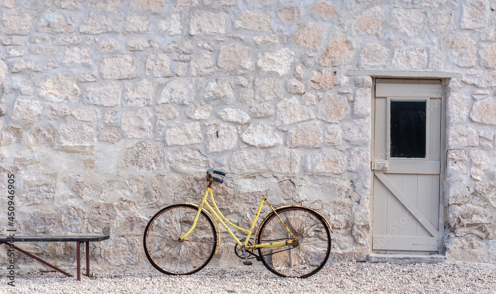 Rusty, old yellow bicycle in front of a stone wall, Rural South Australia
