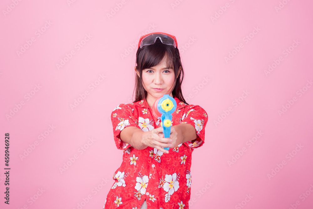Portrait cheerful young asian woman holding plastic water gun Smiling and having fun playing in the water Songkran festival, Thailand. isolated on pink background. Thai New Year's Day. Portrait cheerful young asian woman holding plastic water gun Smiling and having fun playing in the water Songkran festival, Thailand. isolated on pink background. Thai New Year's Day.