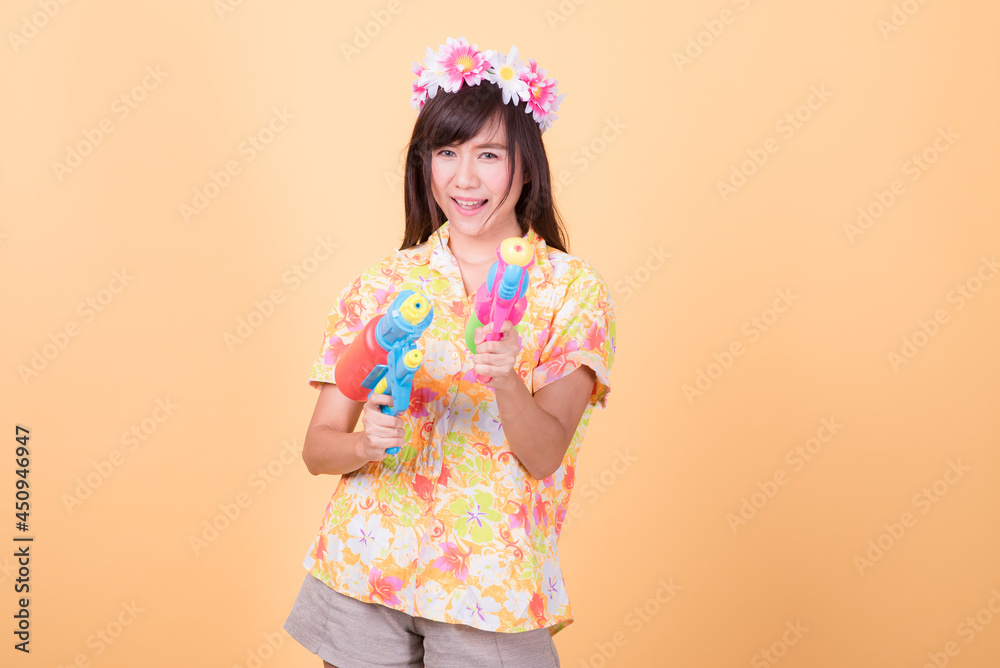 Portrait cheerful young asian woman holding plastic water gun Smiling and having fun playing in the water Songkran festival, Thailand. isolated on pink background. Thai New Year's Day. Portrait cheerful young asian woman holding plastic water gun Smiling and having fun playing in the water Songkran festival, Thailand. isolated on pink background. Thai New Year's Day.