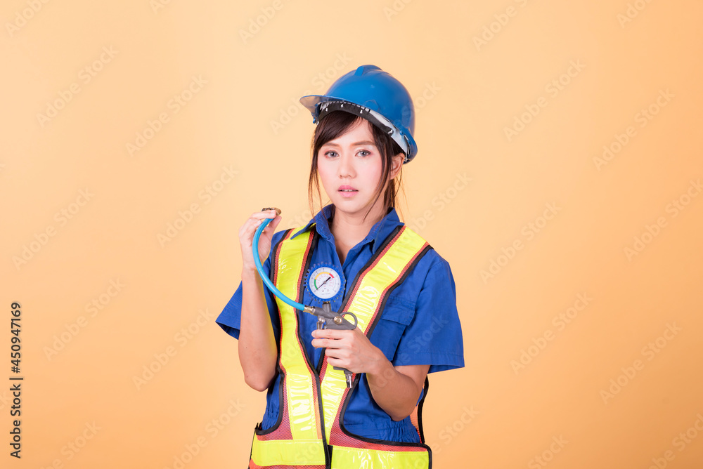 Portrait woman mechanic checking on yellow background