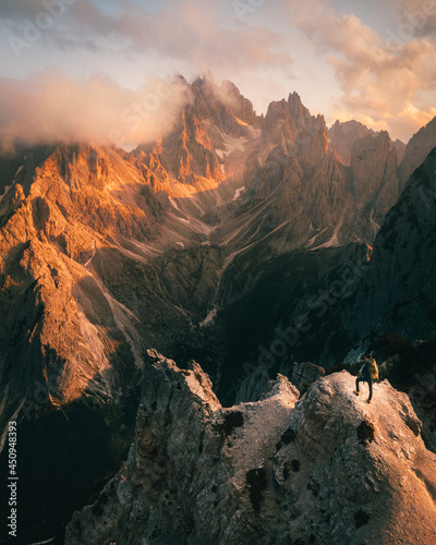 hiker on top of mountain in dolomites at cadini di misurina during sunset in summer