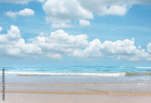 Sand beach on blue sea  white wave under white clouds  pastel blue sky