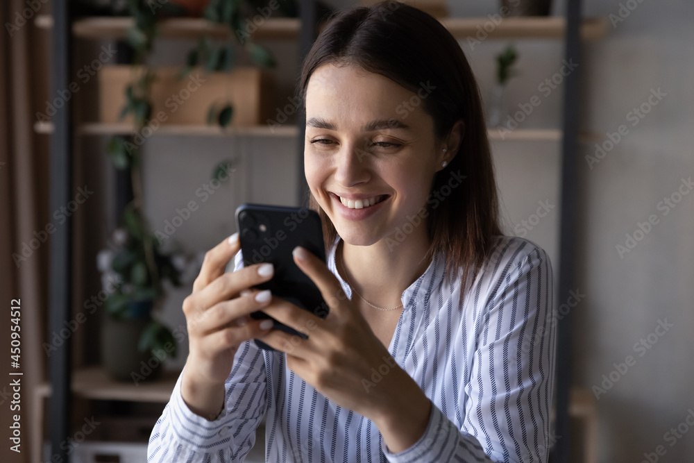 Smiling millennial Caucasian female client or user look at smartphone screen talk speak on webcam video call online. Happy young woman use cellphone browse surf wireless internet on device.
