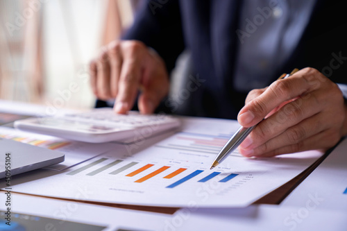 Accountant or banker working process, a Businesswoman using a calculator to calculate the numbers of statistic business profits growth rate on documents graph data, his desk in an office.