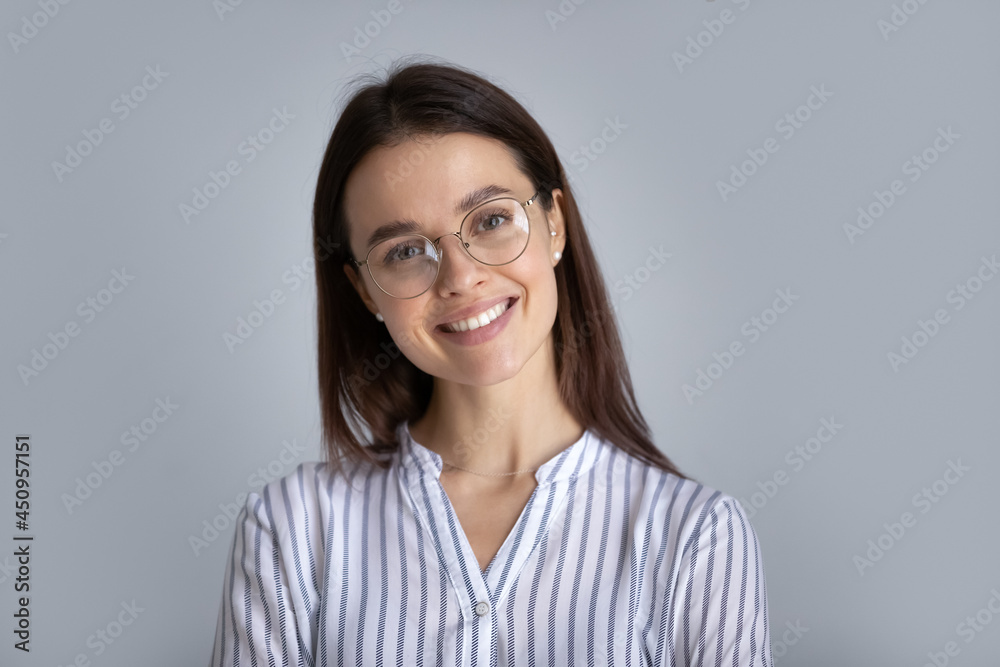 Obraz premium Headshot portrait of happy millennial Caucasian female student in glasses on grey studio background. Profile picture of smiling young businesswoman or woman client in spectacles. Employment concept.