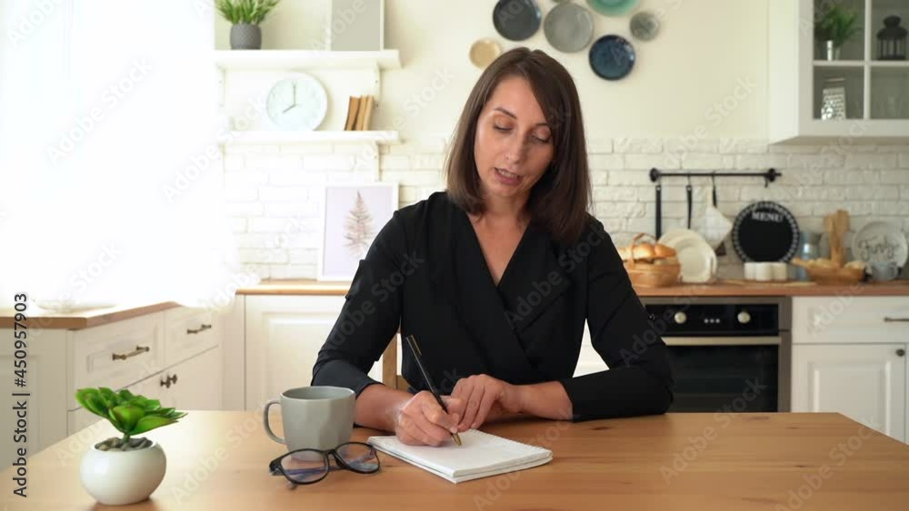 Business woman communicating by video call and writes in a notebook. Webcam view Business woman communicating by video call and writes in a notebook. Webcam view