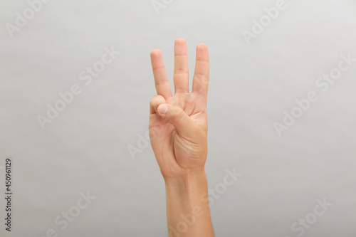 Teenage boy showing three fingers on light background, closeup © New Africa