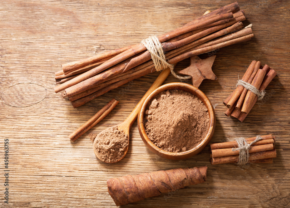 Cinnamon sticks and bowl of cinnamon powder on a wooden table Cinnamon sticks and bowl of cinnamon powder on a wooden table