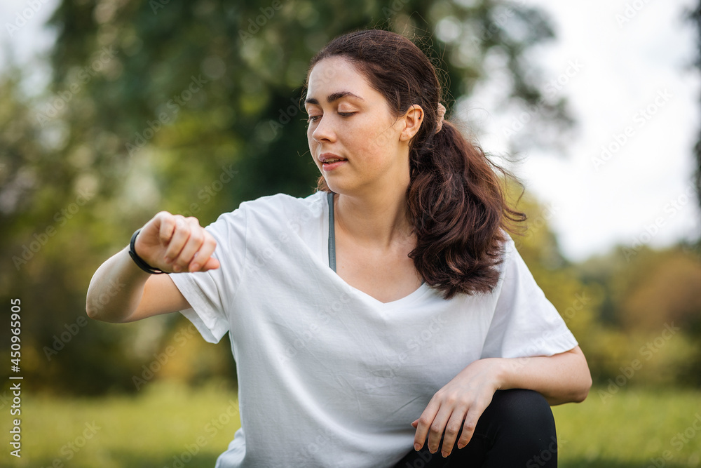Portrait of young caucasian woman checks her smart watch. The concept of a modern device and wellness Portrait of young caucasian woman checks her smart watch. The concept of a modern device and wellness