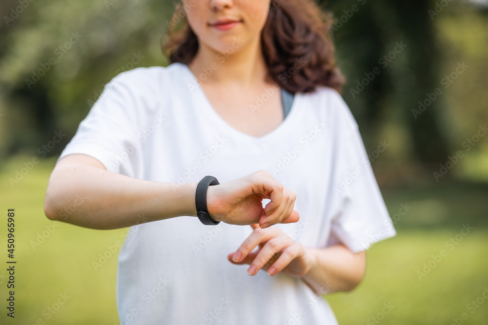 Close up portrait of young woman touch and checks her smart watch. The concept of a modern device and wellness Close up portrait of young woman touch and checks her smart watch. The concept of a modern device and wellness