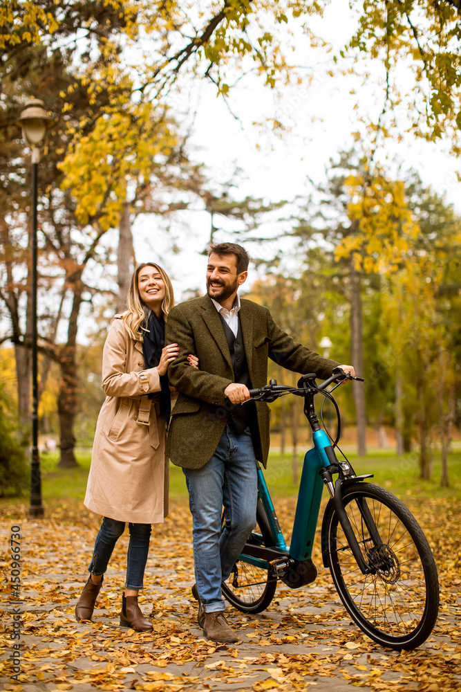 Young couple in the autumn park with electrical bicycle Young couple in the autumn park with electrical bicycle