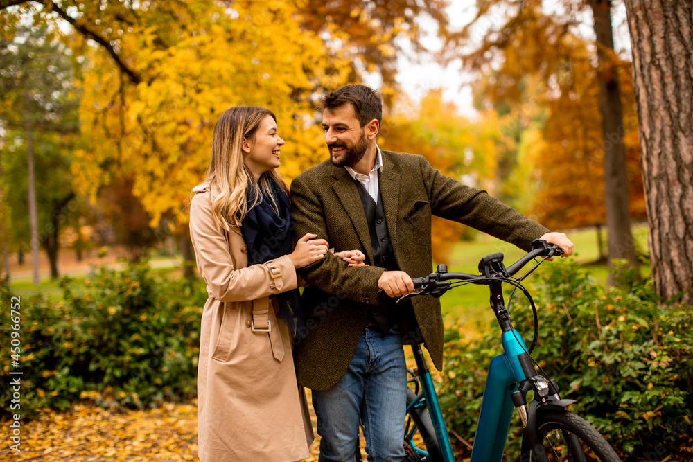 Naklejka premium Young couple in the autumn park with electrical bicycle