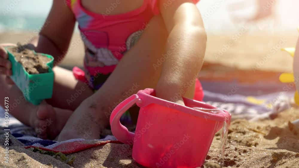 Child playing with water and toys. Joyful nostalgic moment. Kids playing with plastic interactive toys on the beach. Concept of holidays, travel and vacations with the kids. Child playing with water and toys. Joyful nostalgic moment. Kids playing with plastic interactive toys on the beach. Concept of holidays, travel and vacations with the kids.