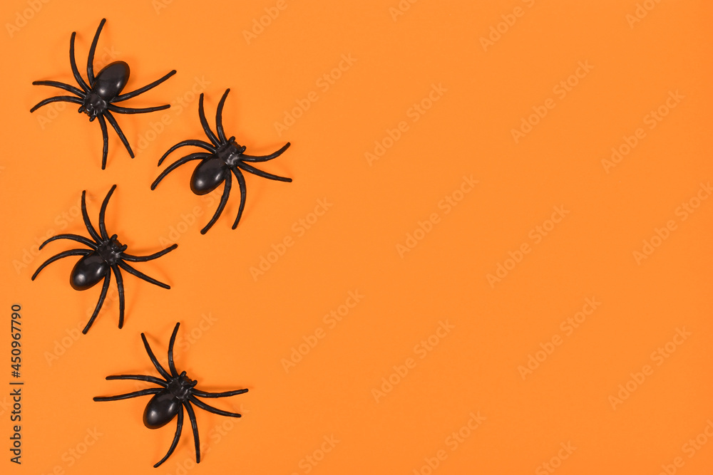Plastic spiders on side of bright orange Halloween background with empty copy space Plastic spiders on side of bright orange Halloween background with empty copy space