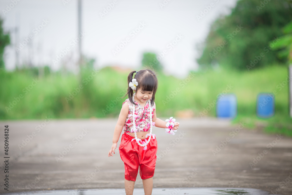 Naklejka premium Close-up background view of a blurred Asian girl running or teasing in the street in front of the house, doing activities together outside the classroom during the holidays.