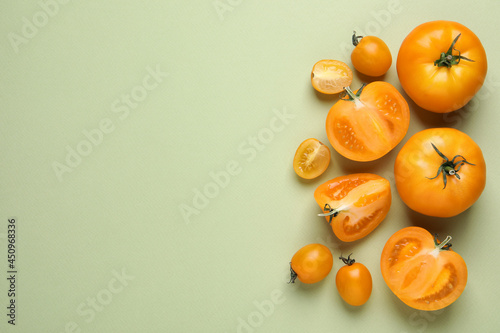Cut and whole ripe yellow tomatoes on light green background, flat lay. Space for text
