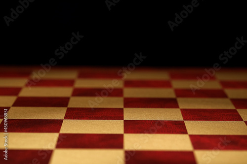 Checkered chessboard on dark background, closeup view