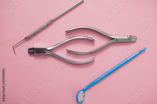 Dental pliers and other dentists instruments on pink background