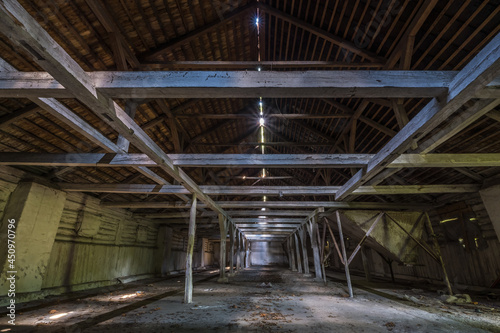 inside dark abandoned ruined wooden decaying hangar with rotting columns