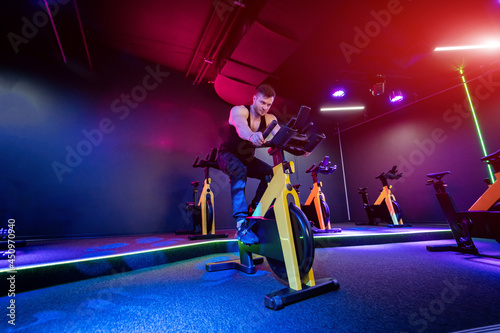 Handsome man training on a cycle at gym. Young active lifestyle adult man cycling.