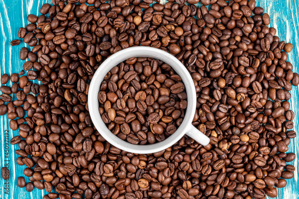Scattered on the table beans of roasted coffee in a white cup. Morning. Cheerfulness Scattered on the table beans of roasted coffee in a white cup. Morning. Cheerfulness