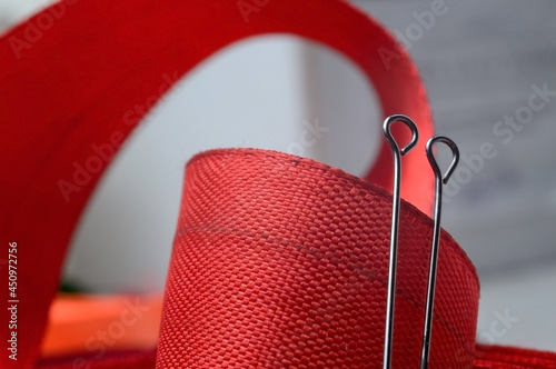 two sewing pins on the background of a red cloth tape. close-up. © Oleg