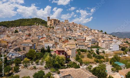 An aerial view with the drone of the mountain village of Moratalla in Spain. You can see the roofs and the church well. It s summer and there are beautiful clouds in the sky.