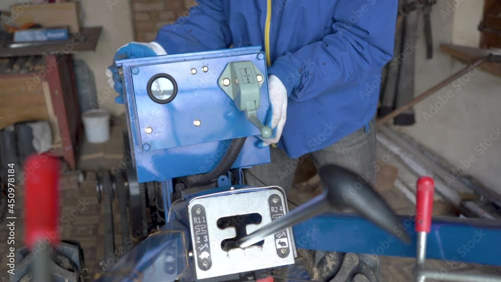 disassembly of the tractor,a man removes an electric panel from a two-wheeled tractor