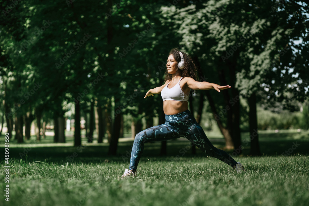 young woman in headphones performing fitness exercises in the pa young woman in headphones performing fitness exercises in the pa