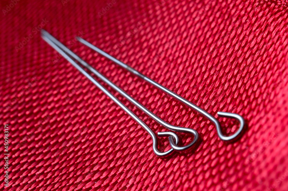 Fototapeta premium three sewing pins on a background of red fabric. close-up.