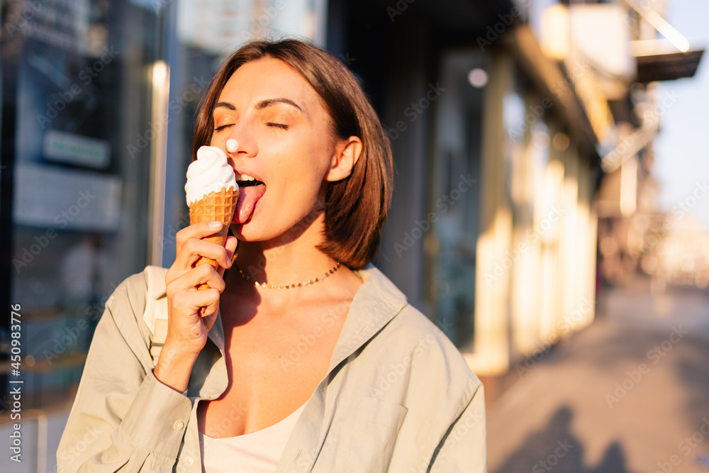 Woman outdoor  at summer sunset time having ice cream cone positive happy playful at city street