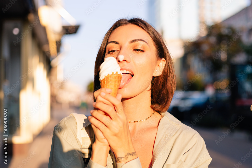 Woman outdoor at summer sunset time having ice cream cone positive happy playful at city street Woman outdoor at summer sunset time having ice cream cone positive happy playful at city street