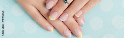Beautiful womans hands with spring summer nail design on blue background