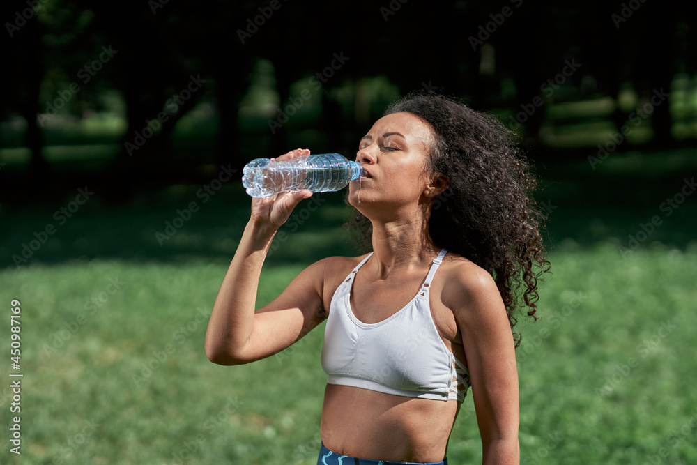 tired young woman drinks water after a sports workout. tired young woman drinks water after a sports workout.