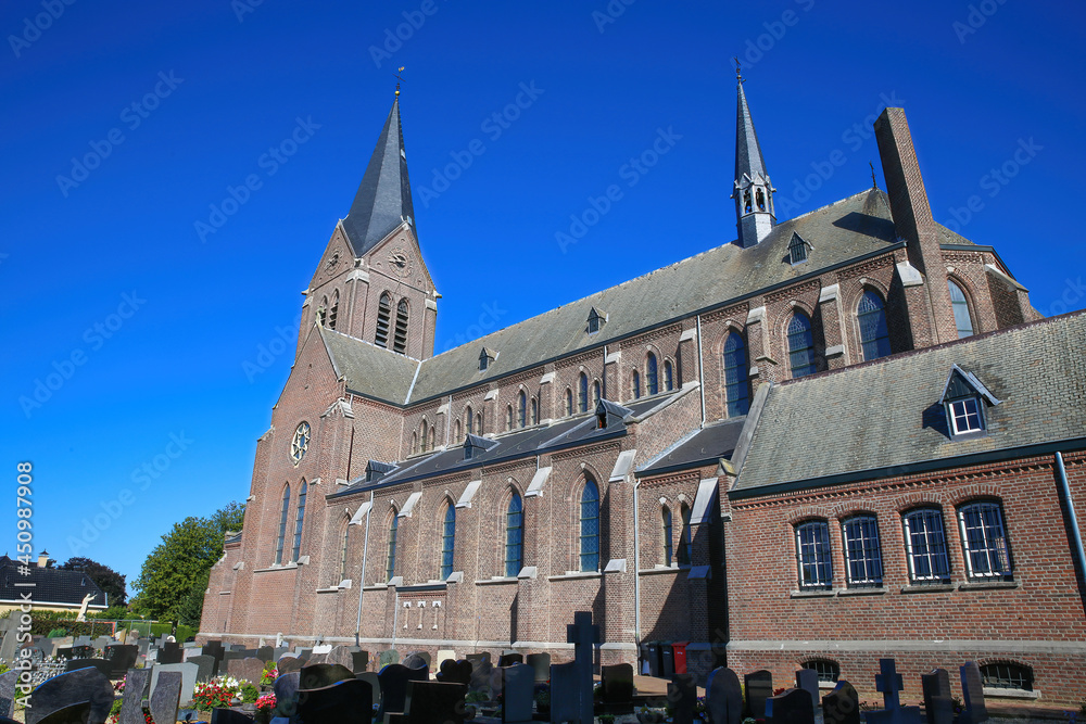 View over old cemetery with gravestones on medieval catholic church against blue summer sky - Kessel (Limburg), Netherlands