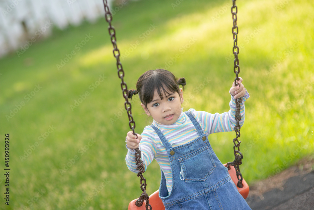 Happy little Asian girl playing swing outdoor in the park Happy little Asian girl playing swing outdoor in the park