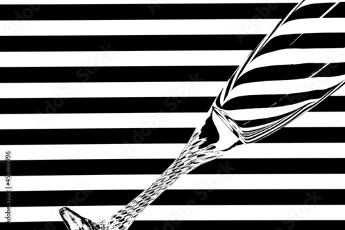 Narrow empty wine glass against black and white stripes creating illusion of refraction of light