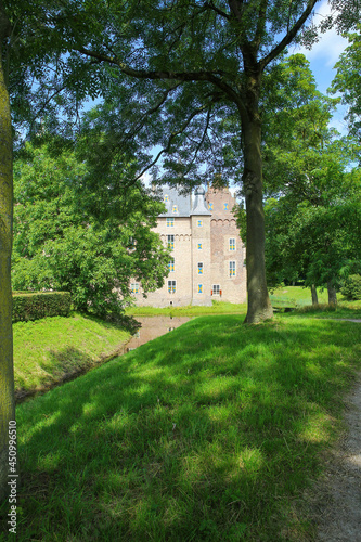 View beyond green trees on dutch water castle from 14th century against blue summer sky © Ralf