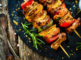 Skewers - grilled meat with fresh vegetables on wooden background
