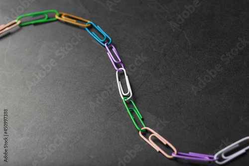 Multi-colored paper clips with a chain on a black background.