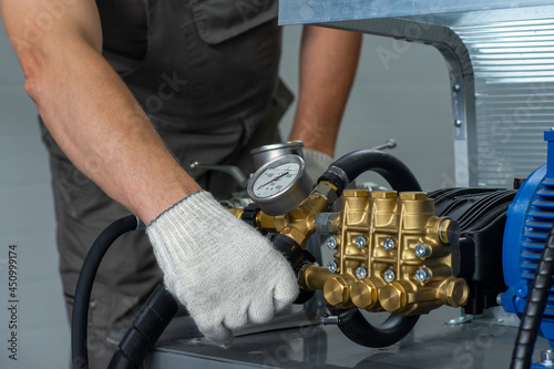 A man's hand in a white glove turns on a set with a pressure gauge for testing high pressure hydraulic hoses. A man in uniform is testing high pressure hoses. Pipe testing system.