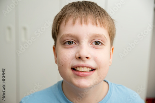Photo of adorable young boy looking at camera. Makes a grimace, laughs.