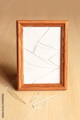 Broken glass on a light wooden surface. Rectangular photo frame.